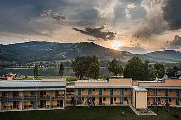 Hotelansicht des JUFA Hotel Stubenbergsee mit Seeblick am Abend